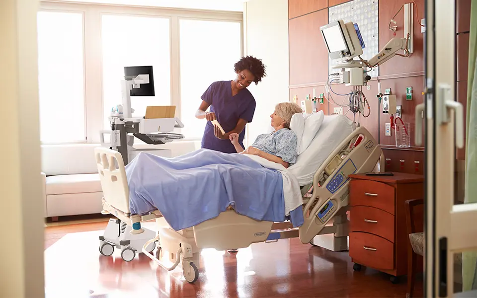 Doctor and patient smiling beside patient bed.