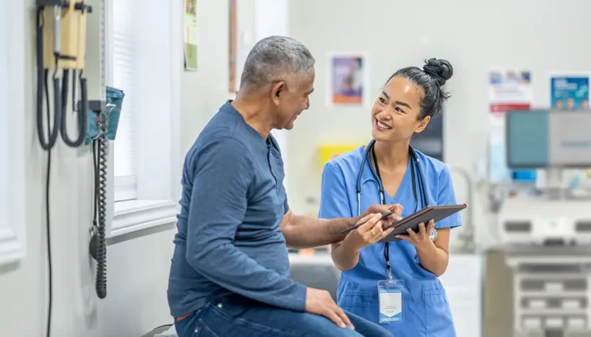A doctor and patient smiling while talking during an office visit.