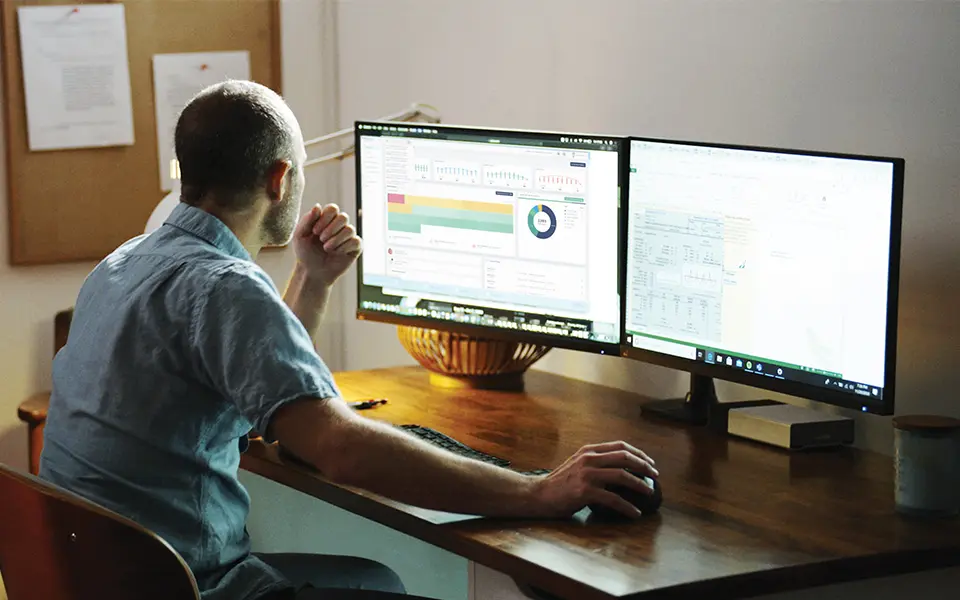 A man sitting at a desk looking at his computer screen.